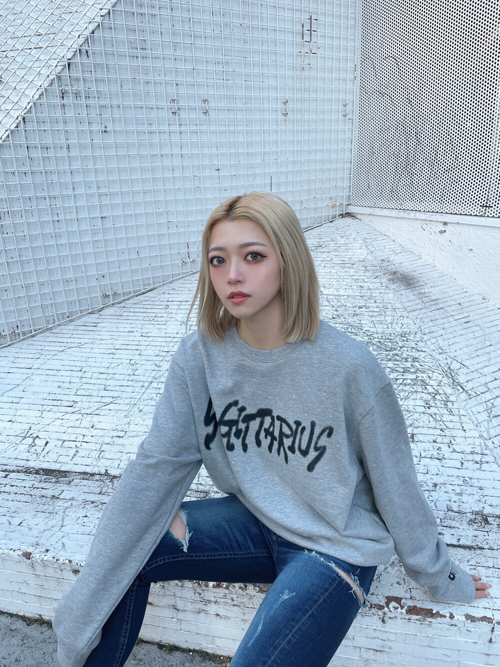 グレー系のスウェット、ブルー系のデニムパンツ、ブラック系のパンプスを着用したレディースの冬コーディネートの3枚目の写真