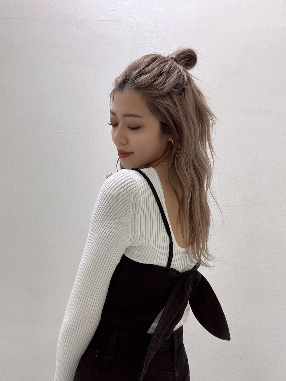 ブラック系のサロペット/オーバーオール、ホワイト系のニット/セーター、ホワイト系のパンプスを着用したレディースの冬コーディネートの6枚目の写真