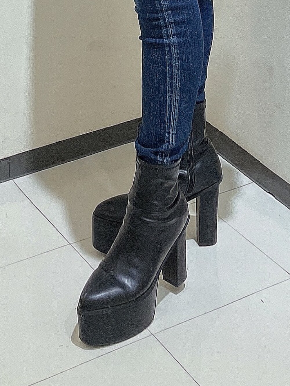 ブラック系のスウェット、ブルー系のデニムパンツ、ブラック系のブーツを着用したレディースの秋コーディネートの7枚目の写真