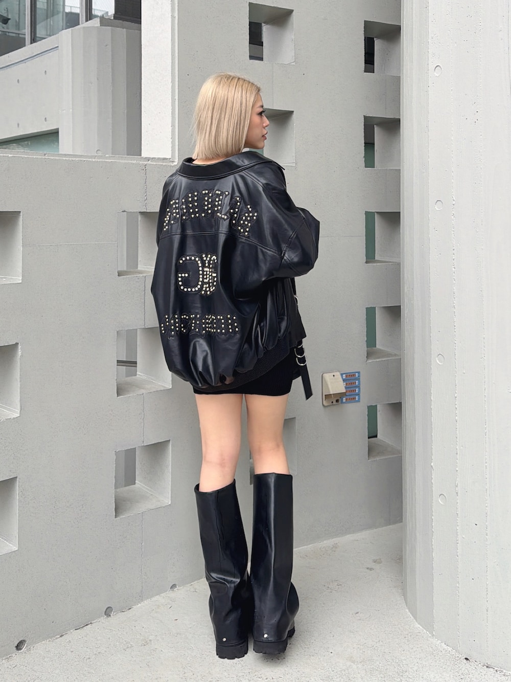 ブラック系のブルゾン、ブラック系のワンピース、ブラック系のブーツを着用したレディースの春コーディネートの2枚目の写真