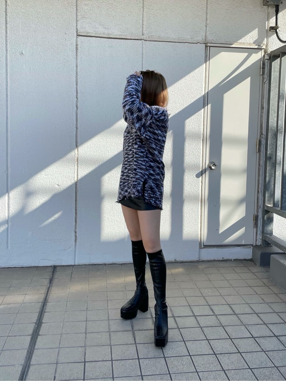 グレー系のニット/セーター、ブラック系のスカート、ブラック系のブーツを着用したレディースの秋コーディネートの2枚目の写真