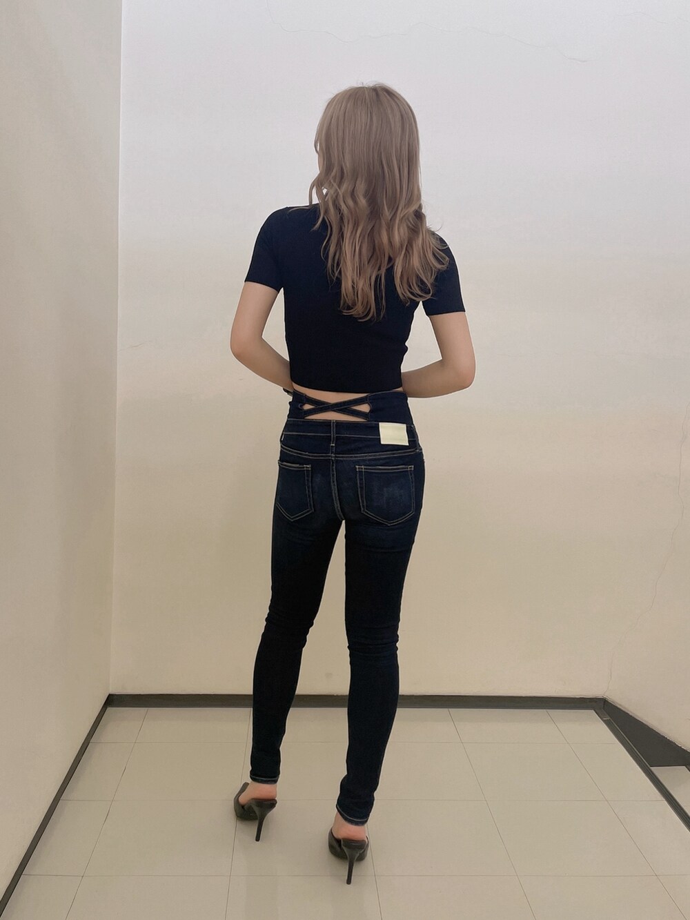 ブラック系のニット/セーター、ブルー系のデニムパンツ、ブラック系のパンプスを着用したレディースの春コーディネートの3枚目の写真
