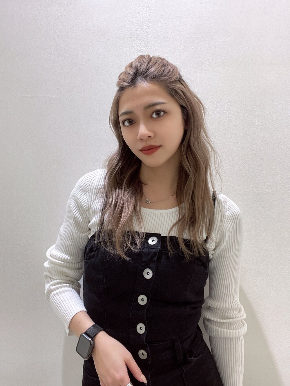 ブラック系のサロペット/オーバーオール、ホワイト系のニット/セーター、ホワイト系のパンプスを着用したレディースの冬コーディネートの5枚目の写真