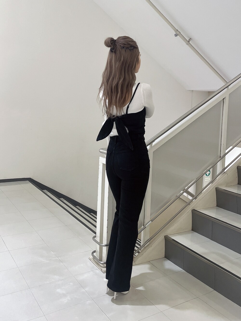 ブラック系のサロペット/オーバーオール、ホワイト系のニット/セーター、ホワイト系のパンプスを着用したレディースの冬コーディネートの4枚目の写真