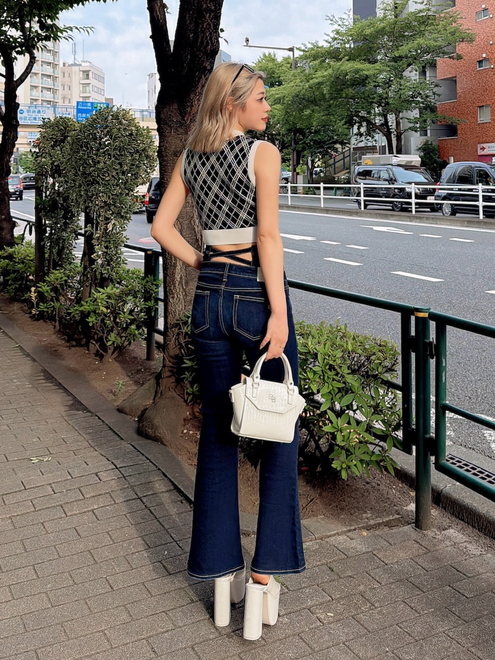 ブラック系のニット/セーター、ブルー系のデニムパンツ、ホワイト系のハンドバッグを着用したレディースの夏コーディネートの3枚目の写真