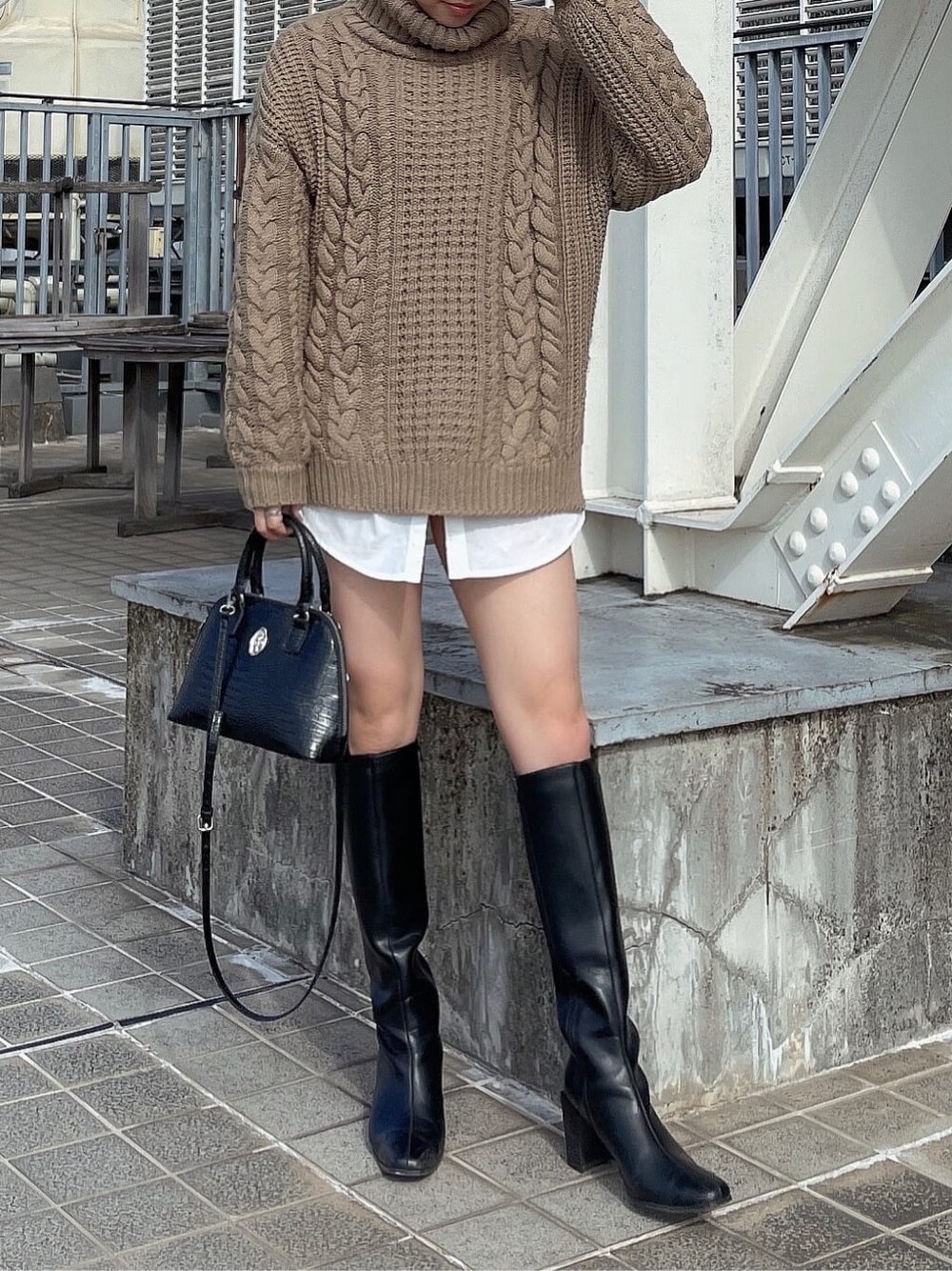 ブラック系のブーツ、ブラック系のデニムパンツ、ベージュ系のニット/セーターを着用したレディースの秋コーディネートの4枚目の写真