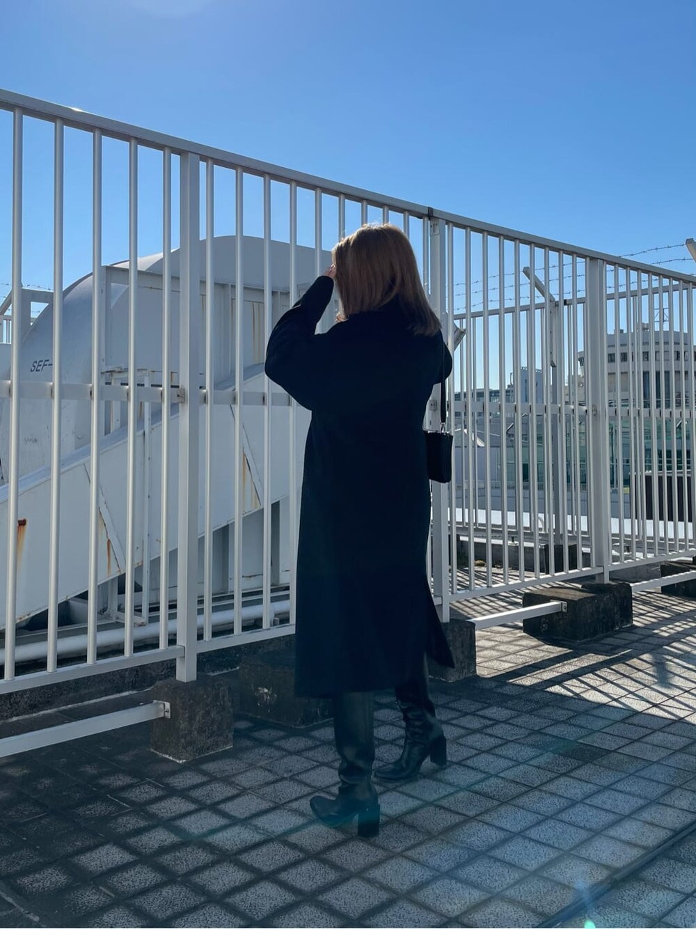 ブラック系のブーツ、ブラック系のニット/セーター、ブラック系のチェスターコートを着用したレディースの秋コーディネートの3枚目の写真