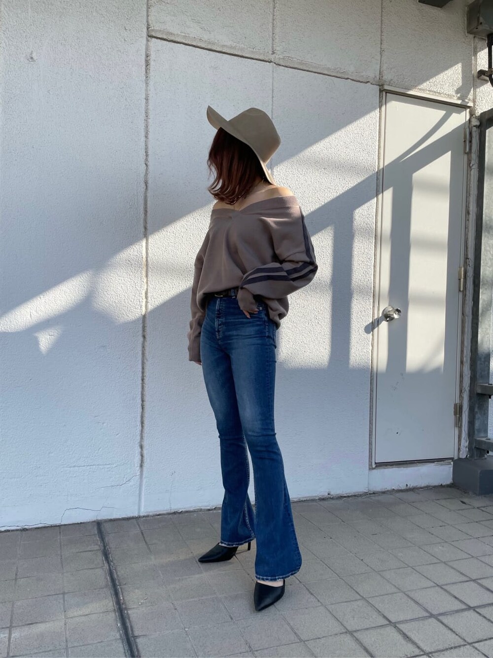 ブラック系のパンプス、ブルー系のデニムパンツ、ベージュ系のニット/セーターを着用したレディースの冬コーディネートの3枚目の写真