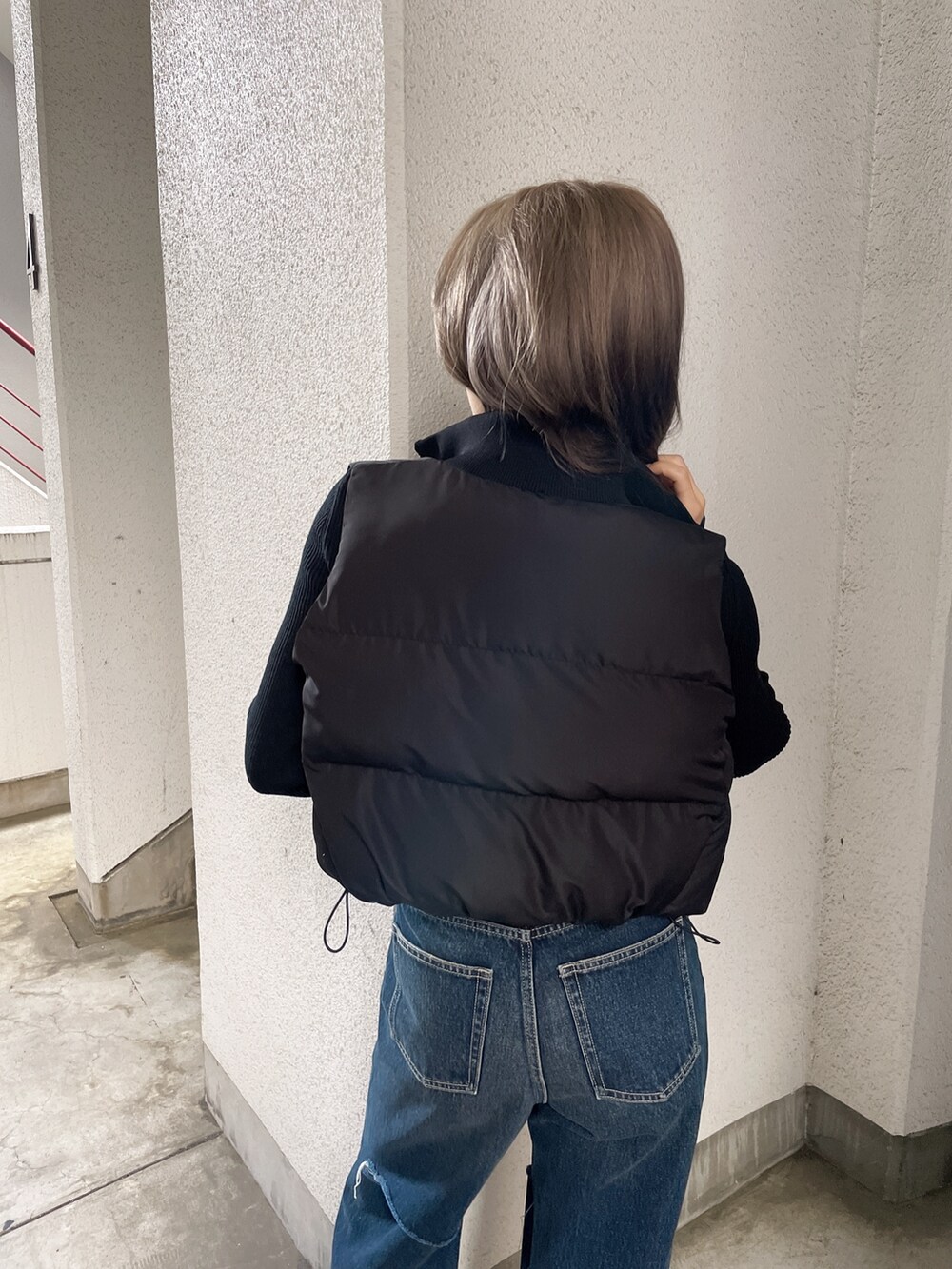 ブラック系のベスト、ブルー系のデニムパンツ、ブラック系のパンプスを着用したレディースの秋コーディネートの4枚目の写真