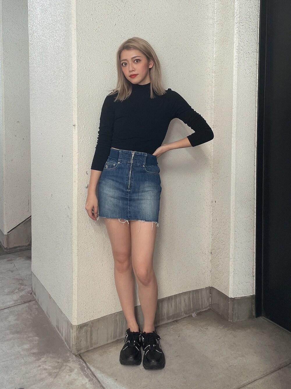 ブラック系のブルゾン、ブルー系のデニムスカート、ブラック系のスニーカーを着用したレディースの秋コーディネートの3枚目の写真