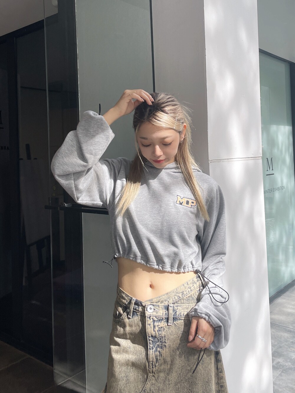 グレー系のパーカー、ブルー系のデニムスカート、ブラック系のパンプスを着用したレディースの秋コーディネートの4枚目の写真