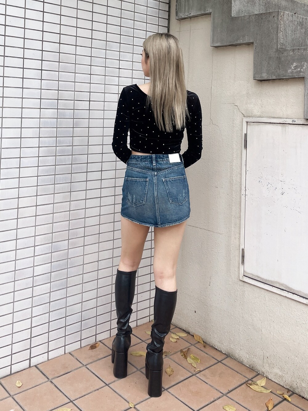 ブラック系のTシャツ/カットソー、ブルー系のデニムスカート、ブラック系のブーツを着用したレディースの秋コーディネートの2枚目の写真