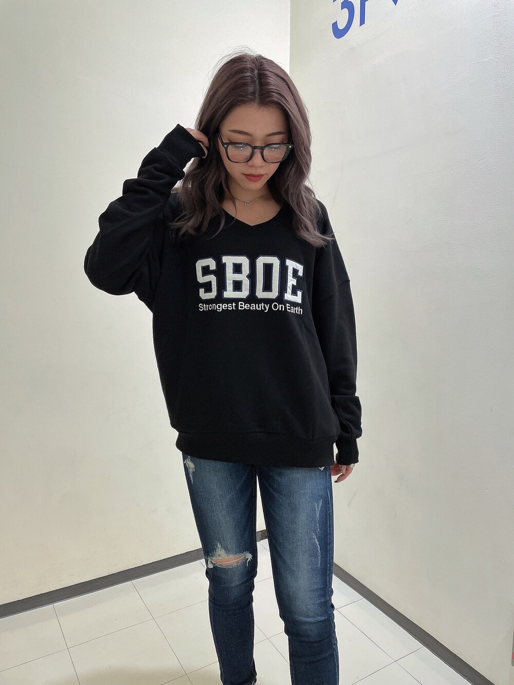 ブラック系のスウェット、ブルー系のデニムパンツ、ブラック系のブーツを着用したレディースの秋コーディネートの4枚目の写真