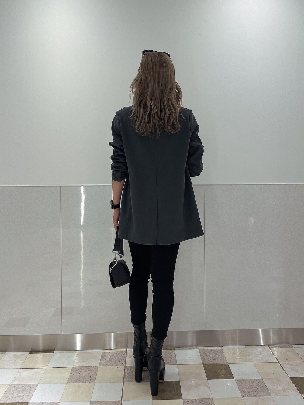 ブラック系のブーツ、ブラック系のデニムパンツ、ブラック系のハンドバッグを着用したレディースの秋コーディネートの2枚目の写真