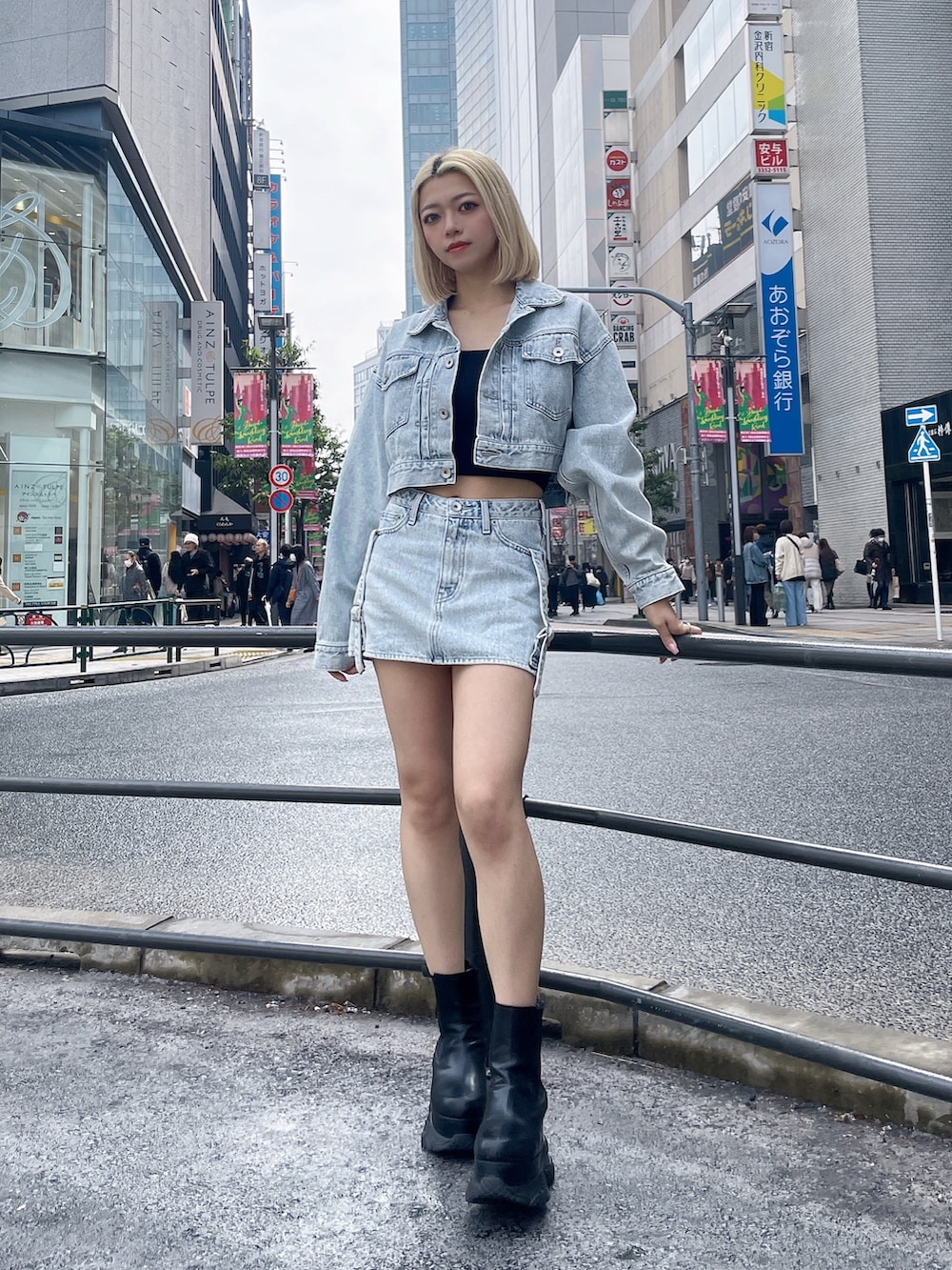 ブルー系のデニムジャケット、ブルー系のデニムスカート、ブラック系のブーツを着用したレディースの春コーディネートの2枚目の写真