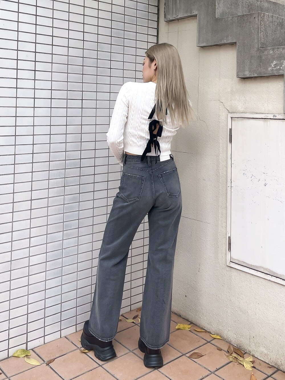 ホワイト系のニット/セーター、ブラック系のデニムパンツを着用したレディースの秋コーディネートの3枚目の写真