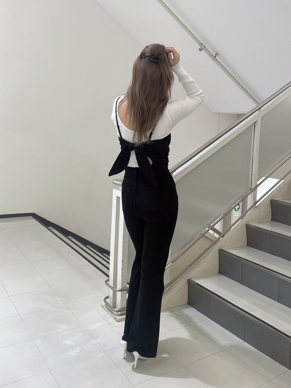 ブラック系のサロペット/オーバーオール、ホワイト系のニット/セーター、ホワイト系のパンプスを着用したレディースの冬コーディネートの3枚目の写真