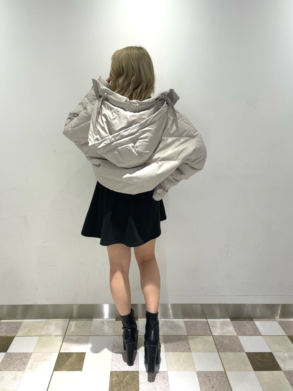 ブラック系のワンピース、ブラック系のブーツ、ホワイト系のダウンジャケット/コートを着用したレディースの冬コーディネートの2枚目の写真