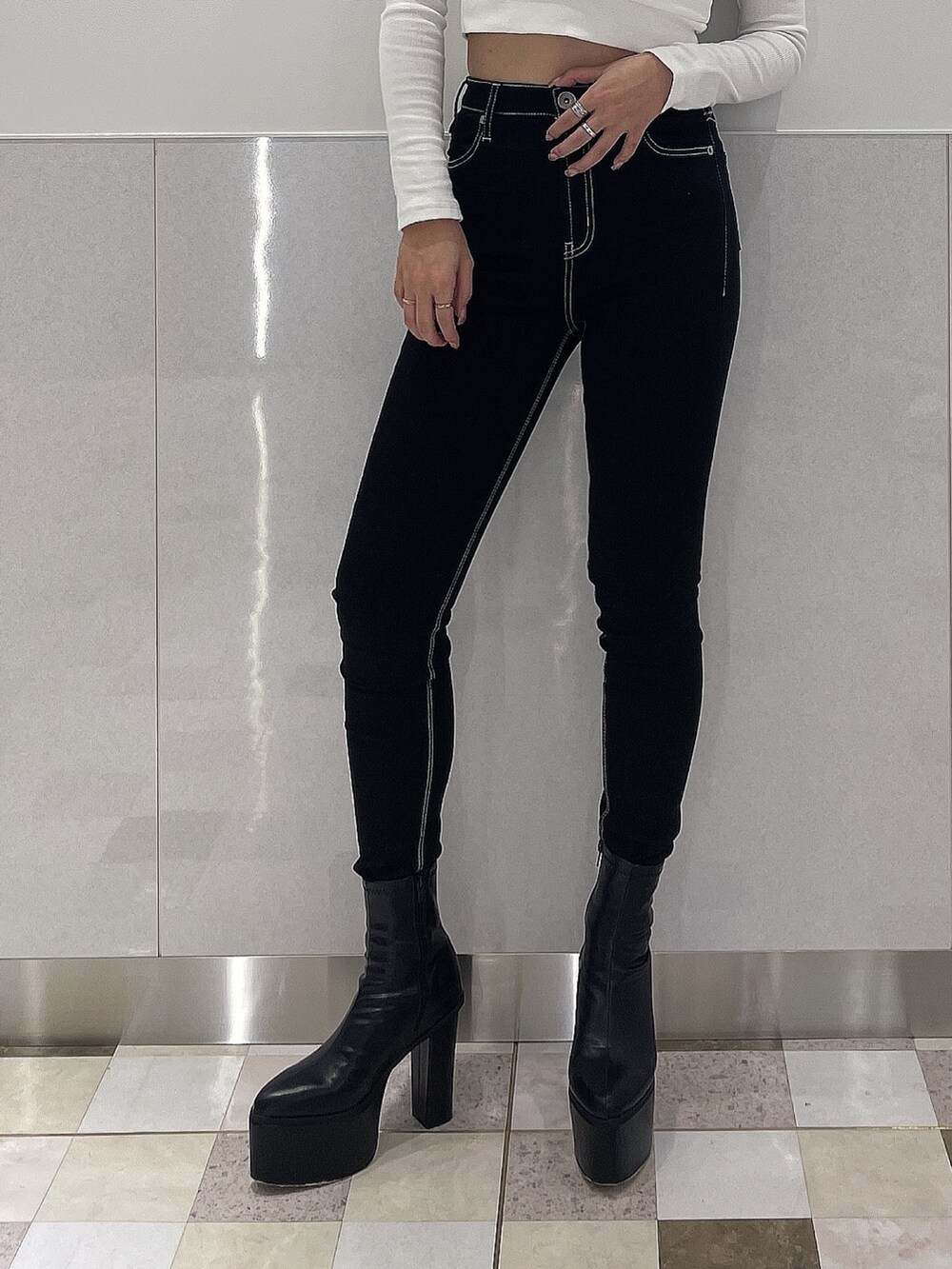 ブラック系のブーツ、ブラック系のデニムパンツ、ブラック系のハンドバッグを着用したレディースの秋コーディネートの6枚目の写真