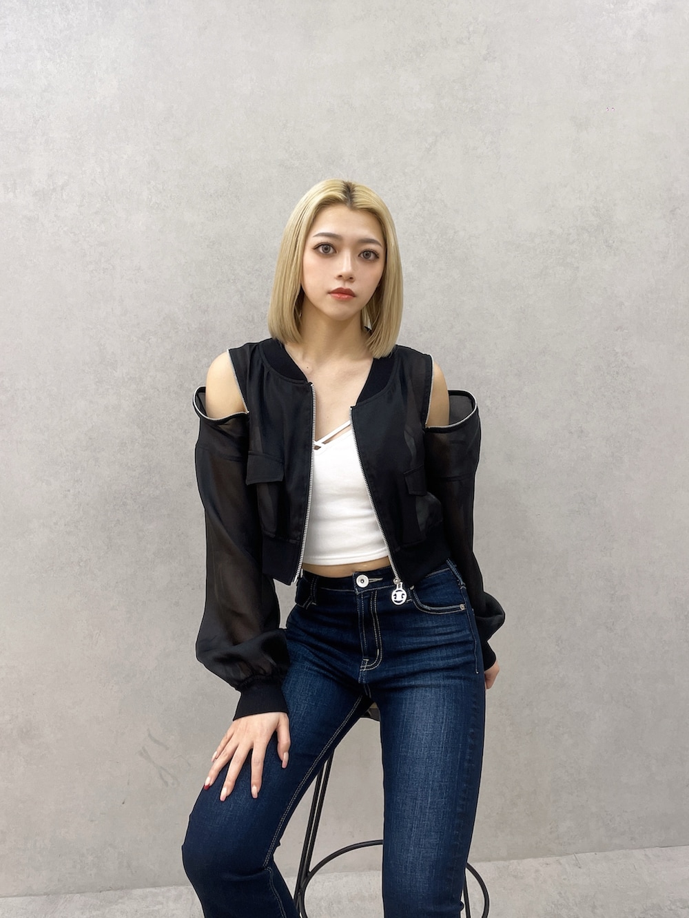 ブルー系のデニムパンツ、ホワイト系のキャミソール、ブラック系のブルゾンを着用したレディースの春コーディネートの4枚目の写真