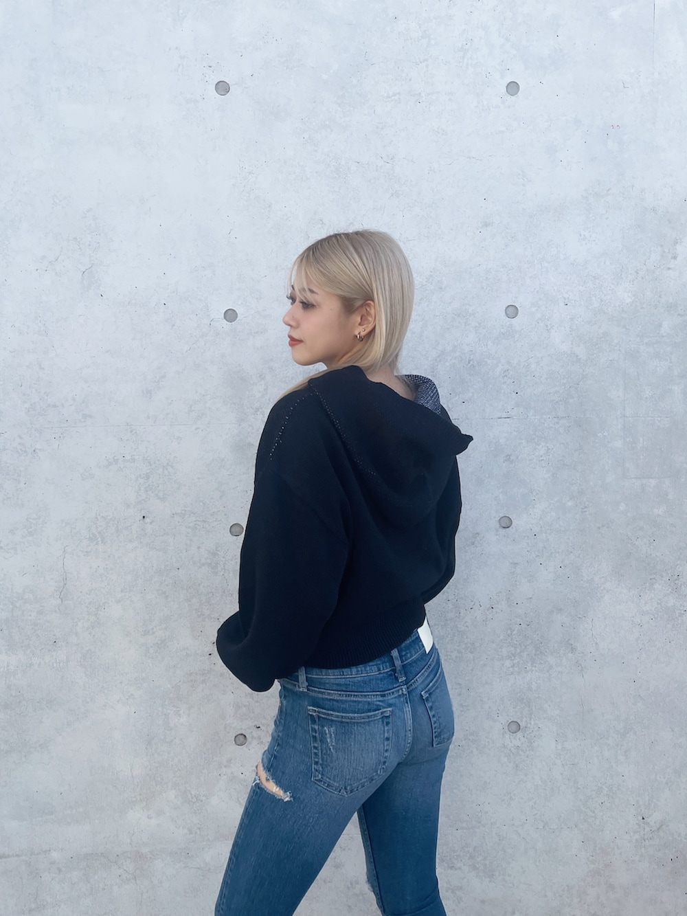 ブラック系のニット/セーター、ブルー系のデニムパンツ、ブラック系のブーツを着用したレディースの冬コーディネートの4枚目の写真