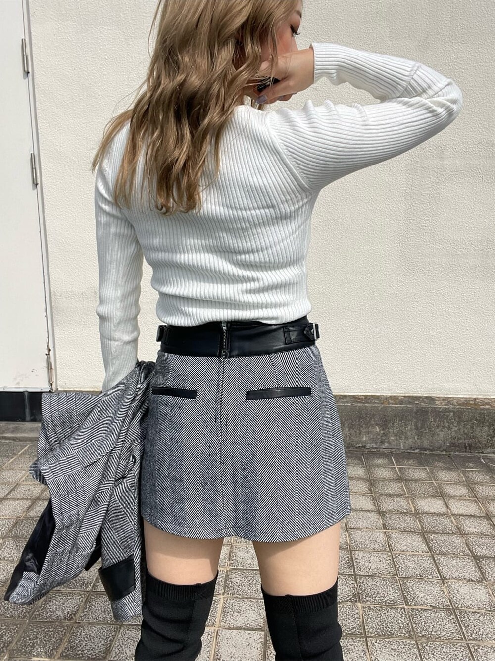 ブラック系のライダースジャケット、ホワイト系のニット/セーター、ブラック系のスカートを着用したレディースの秋コーディネートの5枚目の写真