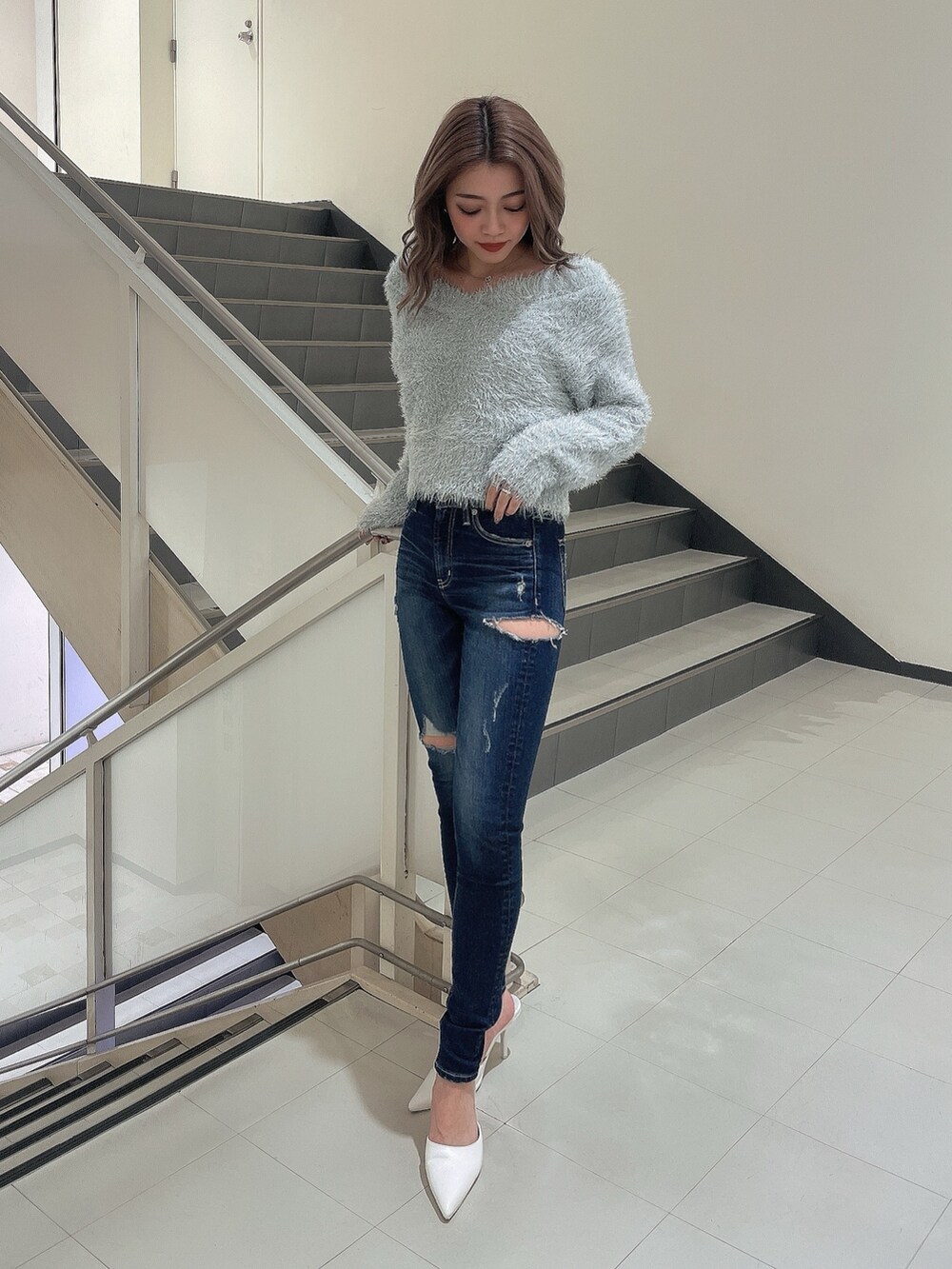 グレー系のニット/セーター、ブルー系のデニムパンツ、ホワイト系のパンプスを着用したレディースの冬コーディネートの2枚目の写真