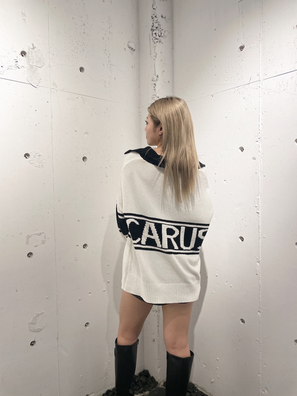 ホワイト系のニット/セーター、ブラック系のスカート、ブラック系のブーツを着用したレディースの秋コーディネートの5枚目の写真