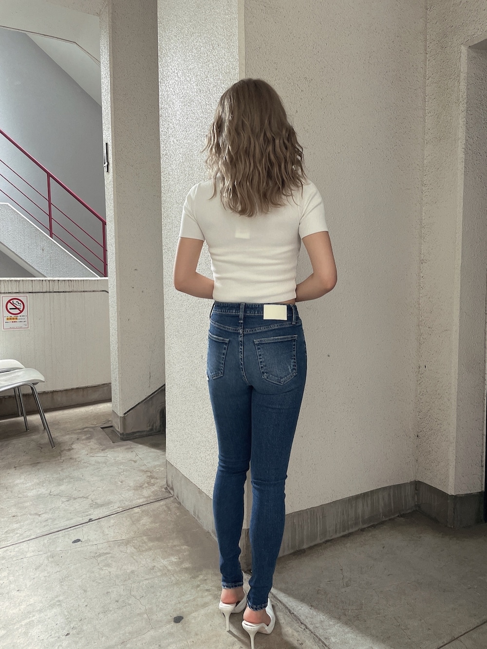 ブルー系のデニムパンツ、ホワイト系のニット/セーター、ホワイト系のパンプスを着用したレディースの夏コーディネートの3枚目の写真