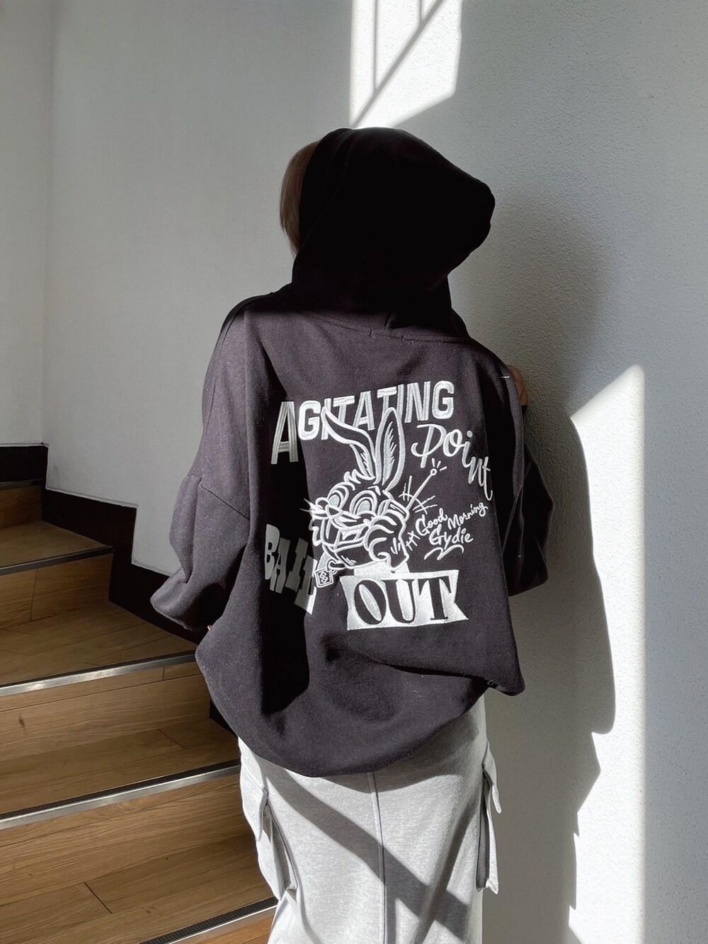 ブラック系のパーカー、グレー系のスカート、ブラック系のスニーカーを着用したレディースの冬コーディネートの3枚目の写真