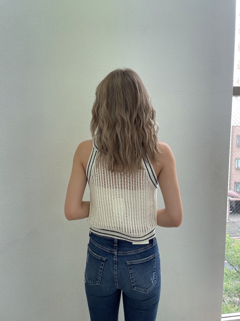 ブルー系のデニムパンツ、ホワイト系のパンプス、ホワイト系のニット/セーターを着用したレディースの夏コーディネートの4枚目の写真