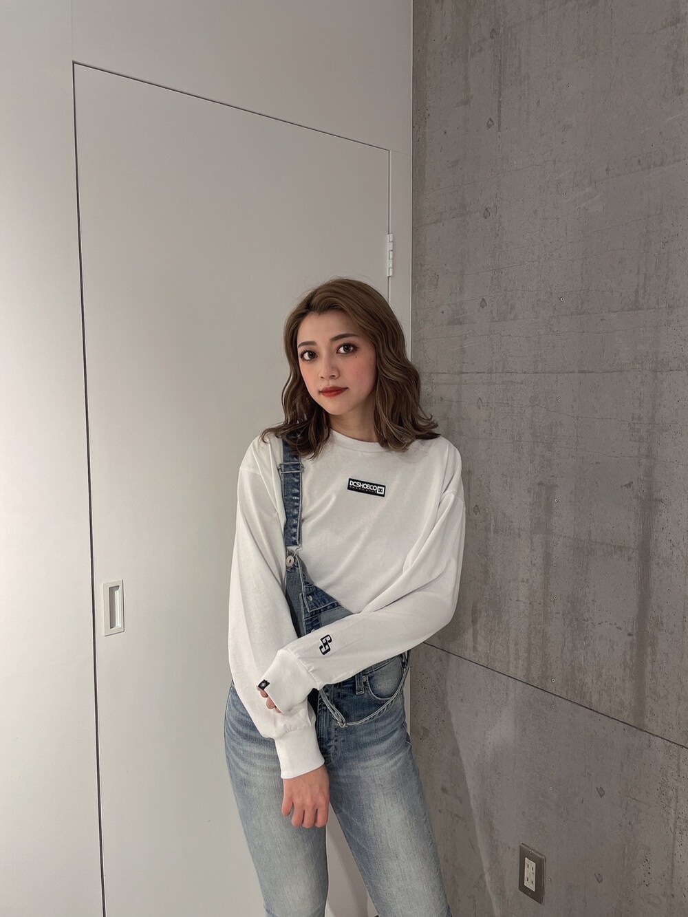 ホワイト系のTシャツ/カットソー、ブルー系のサロペット/オーバーオール、ホワイト系のパンプスを着用したレディースの冬コーディネートの5枚目の写真