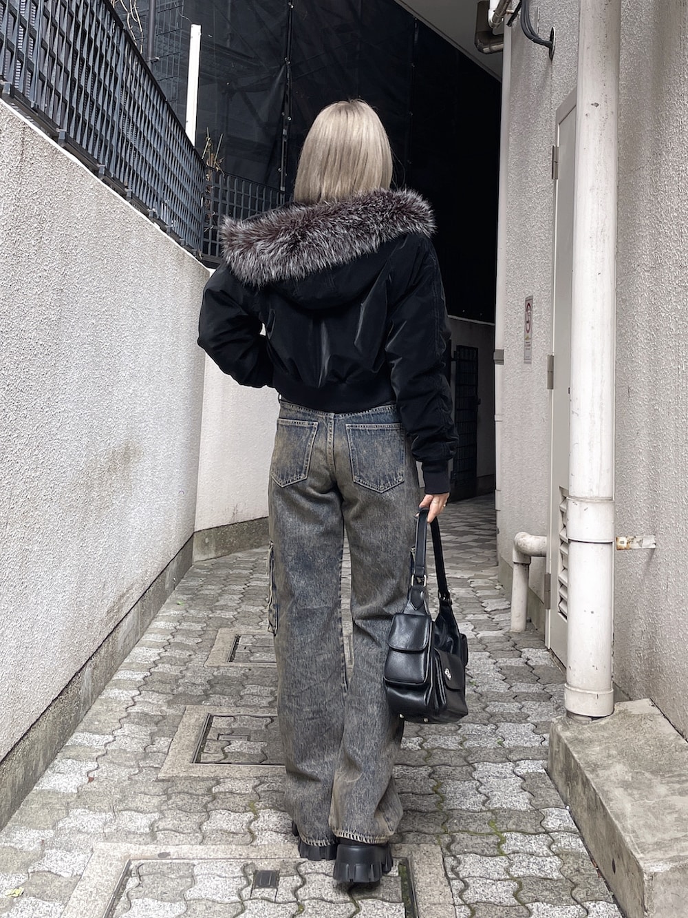 ブラック系のブルゾン、ブラック系のデニムパンツ、ブラック系のブーツを着用したレディースの秋コーディネートの2枚目の写真