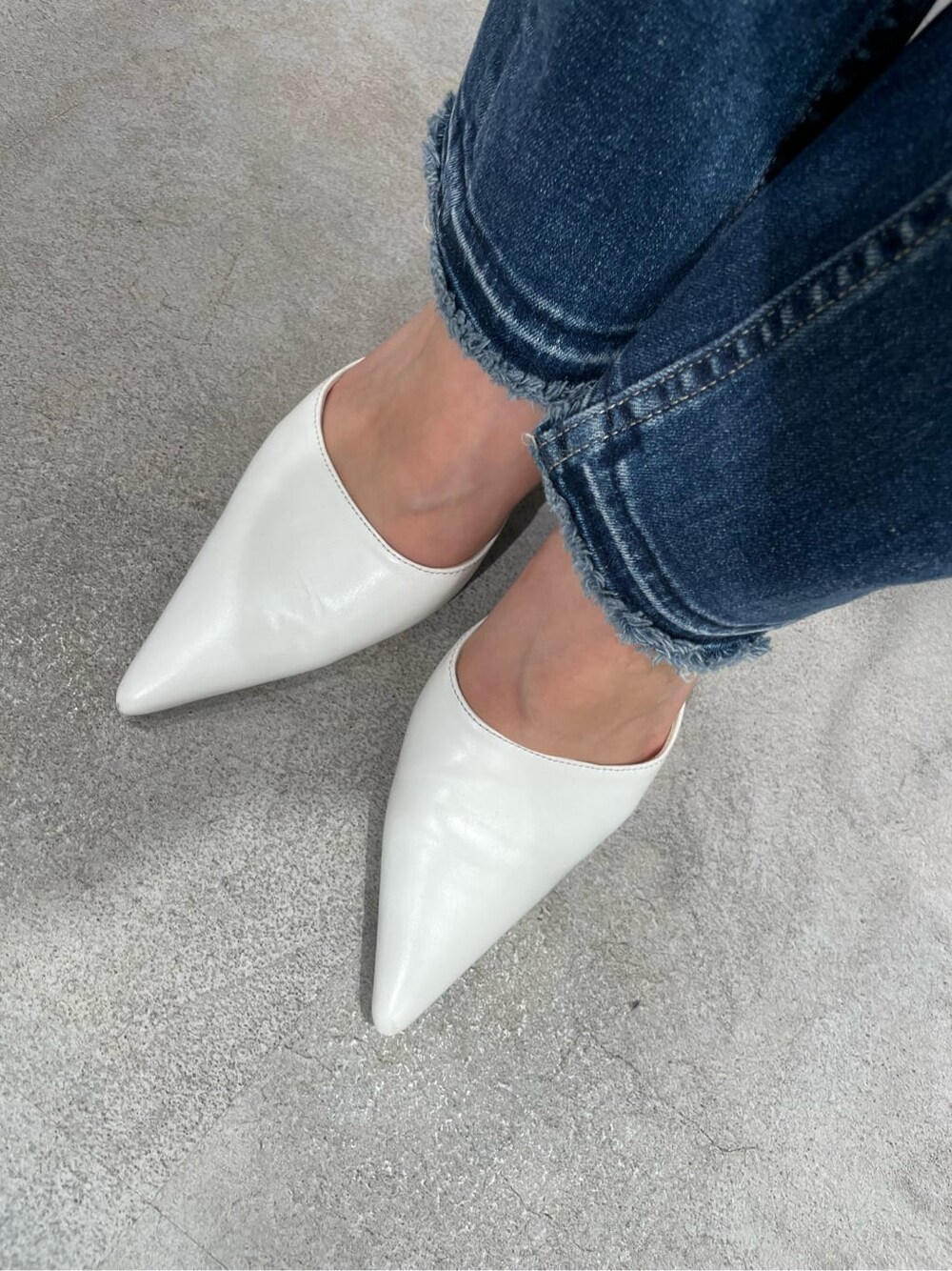 ホワイト系のニット/セーター、ホワイト系のパンプス、ブルー系のデニムパンツを着用したレディースの秋コーディネートの7枚目の写真