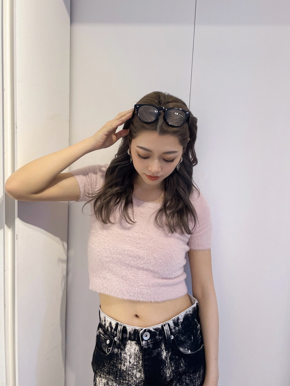 ピンク系のニット/セーター、ブラック系のデニムパンツ、ブラック系のパンプスを着用したレディースの夏コーディネートの3枚目の写真