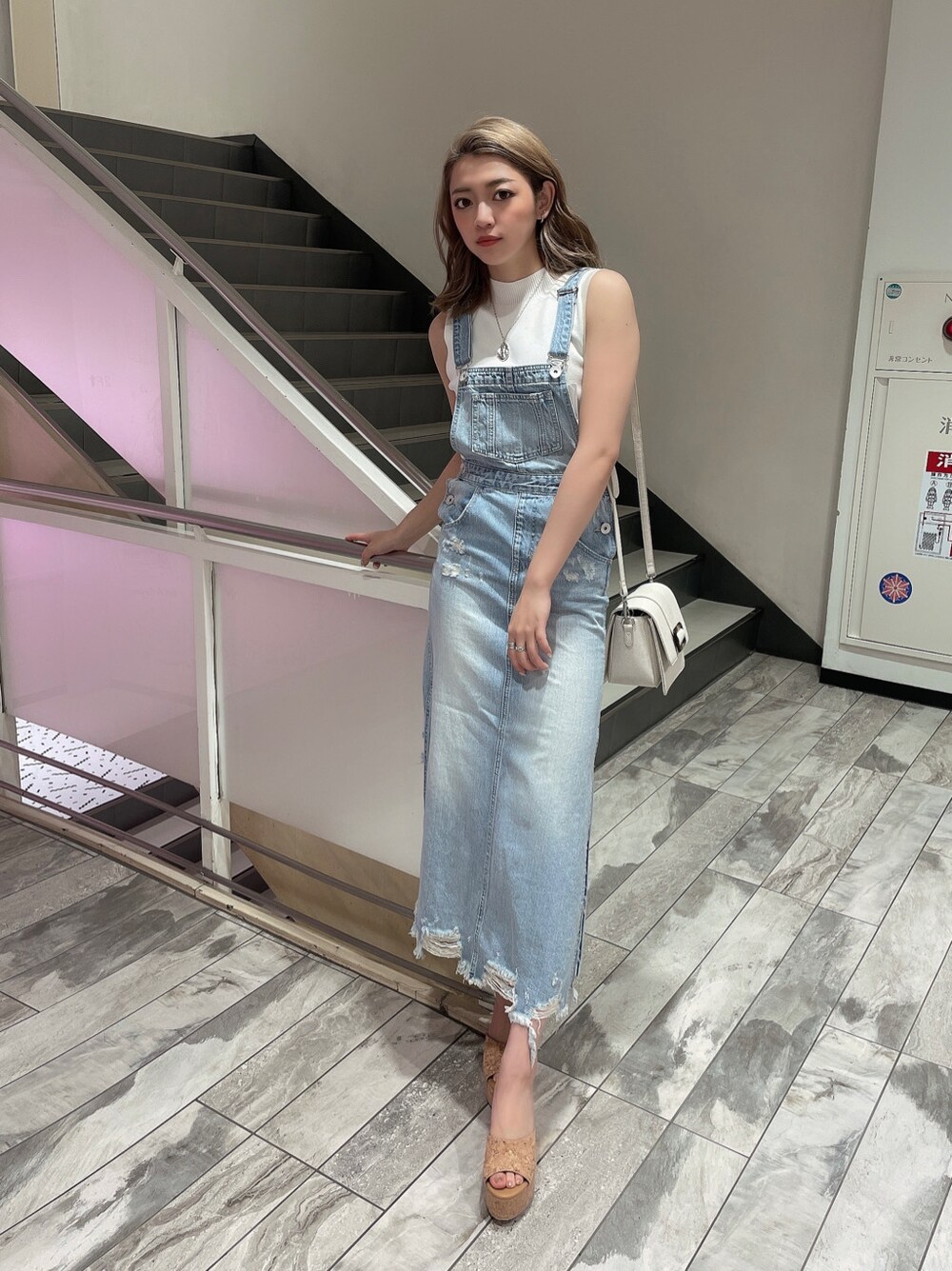 ブルー系のジャンパースカート、ベージュ系のサンダル、ホワイト系のニット/セーターを着用したレディースの春コーディネートの2枚目の写真