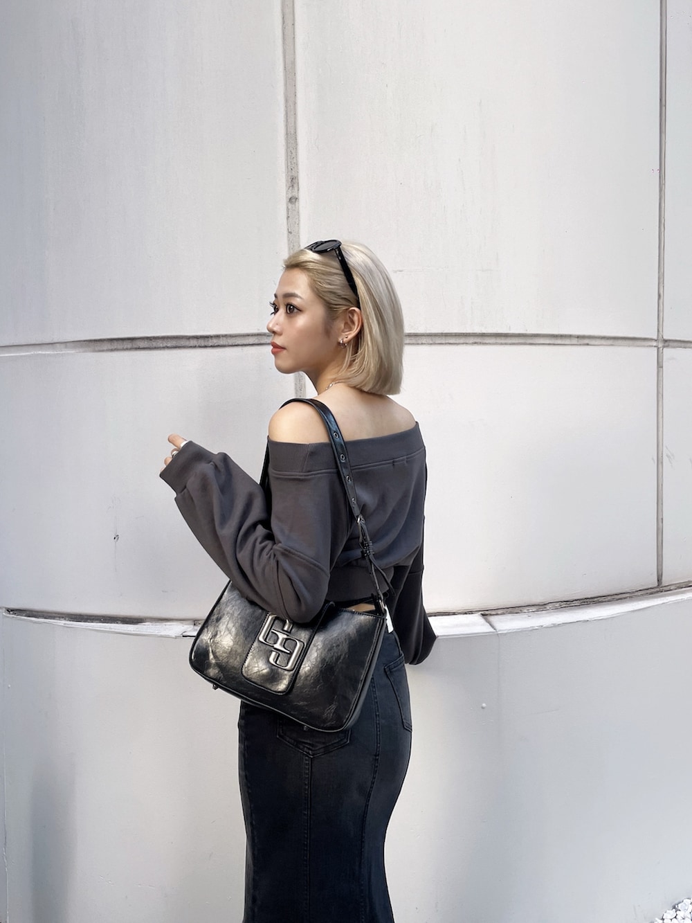 グレー系のTシャツ/カットソー、ブラック系のデニムスカート、ブラック系のハンドバッグを着用したレディースの秋コーディネートの3枚目の写真