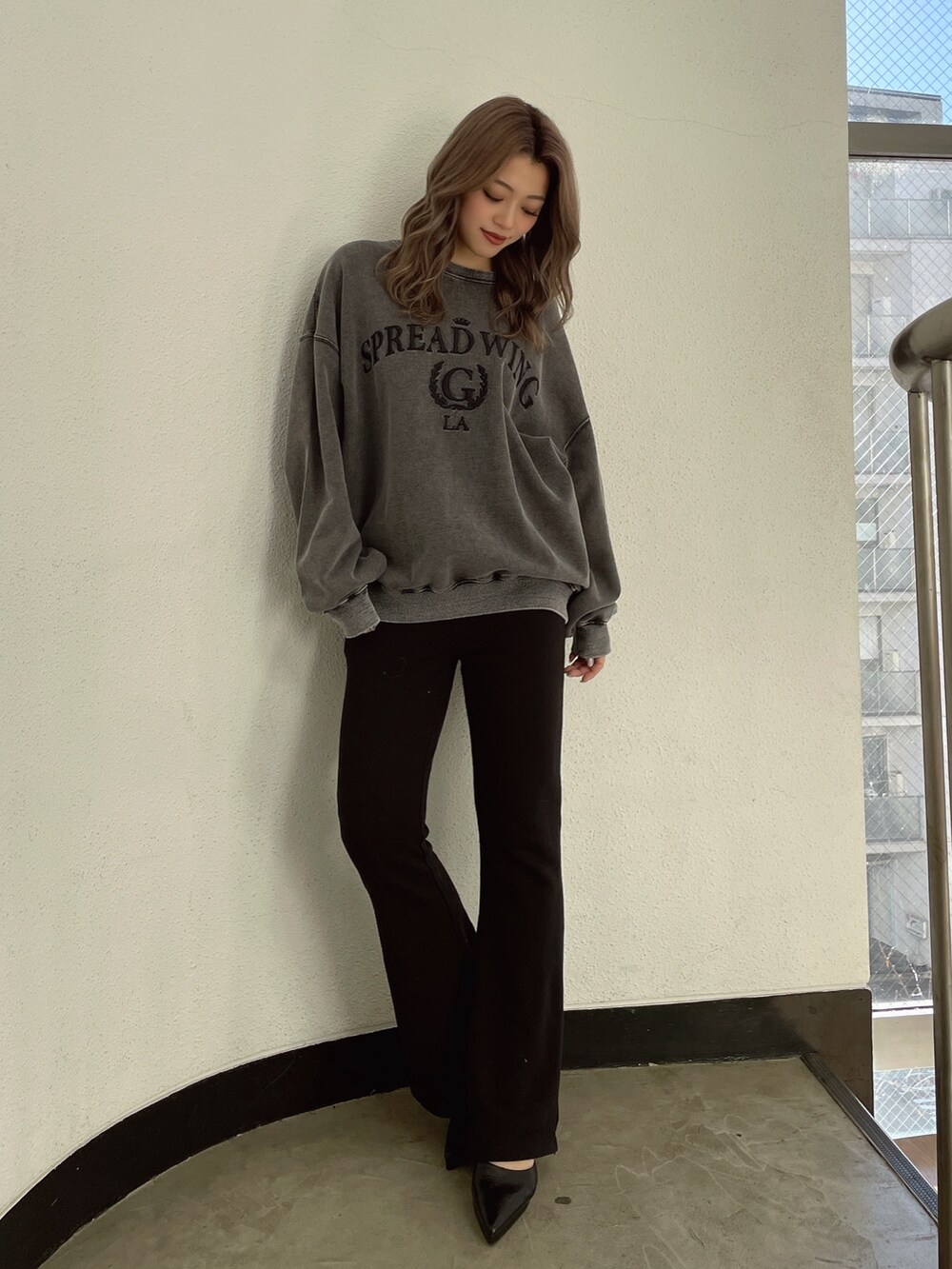 グレー系のスウェット、ブラック系のスウェットパンツ、ブラック系のパンプスを着用したレディースの冬コーディネートの2枚目の写真