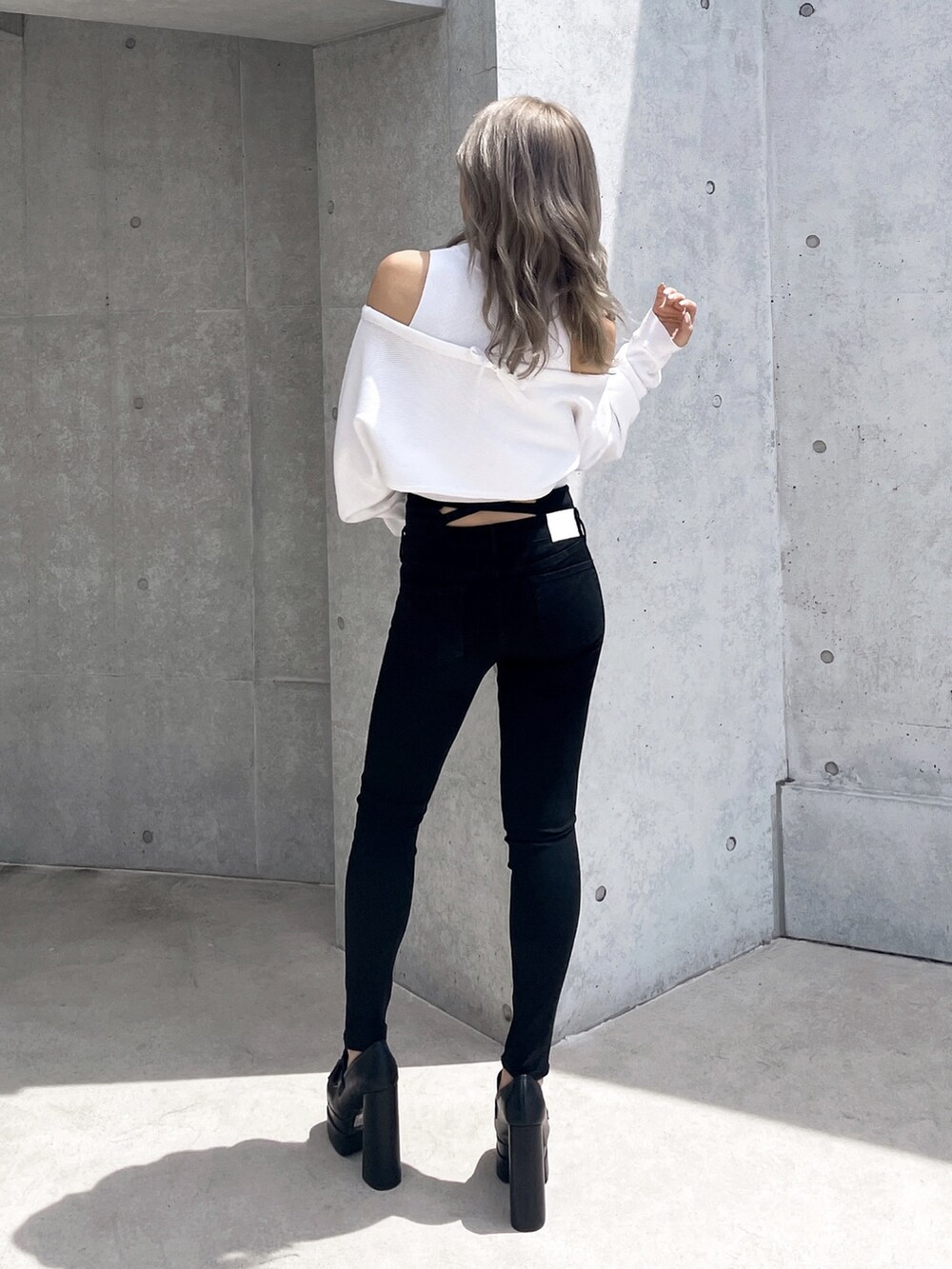 ホワイト系のアンサンブル、ブラック系のデニムパンツ、ブラック系のパンプスを着用したレディースの秋コーディネートの2枚目の写真