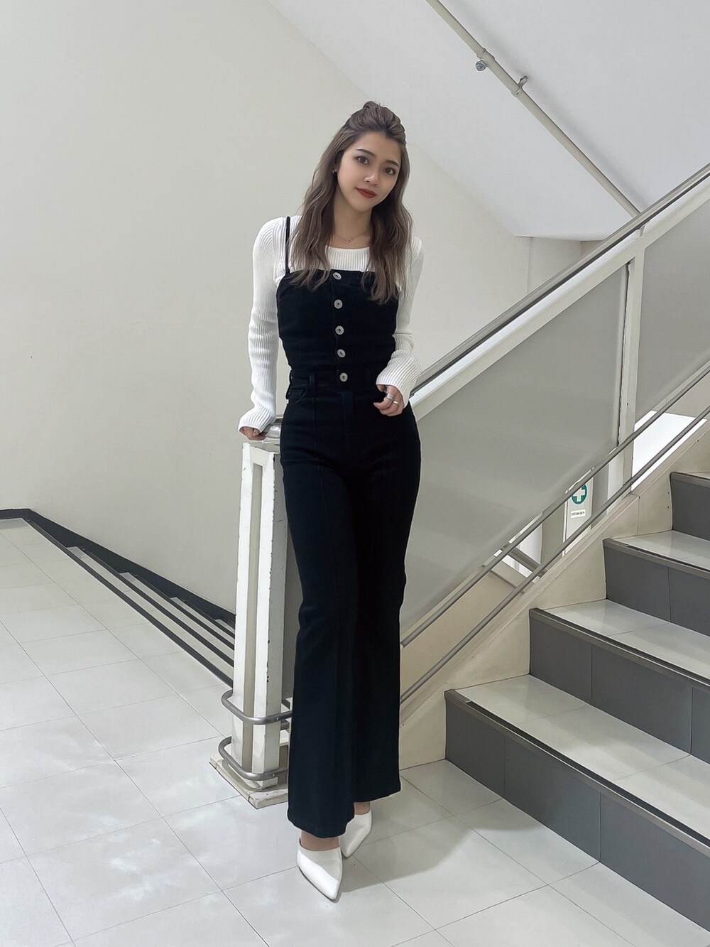 ブラック系のサロペット/オーバーオール、ホワイト系のニット/セーター、ホワイト系のパンプスを着用したレディースの冬コーディネートの2枚目の写真