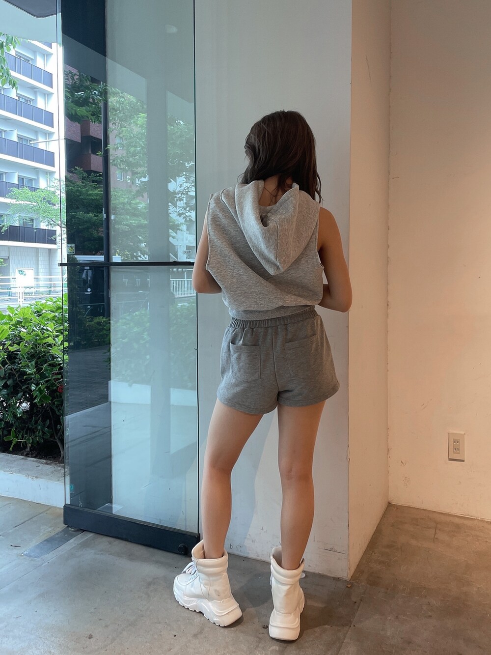 グレー系のパーカー、グレー系のスウェットパンツ、ホワイト系のスニーカーを着用したレディースの夏コーディネートの2枚目の写真