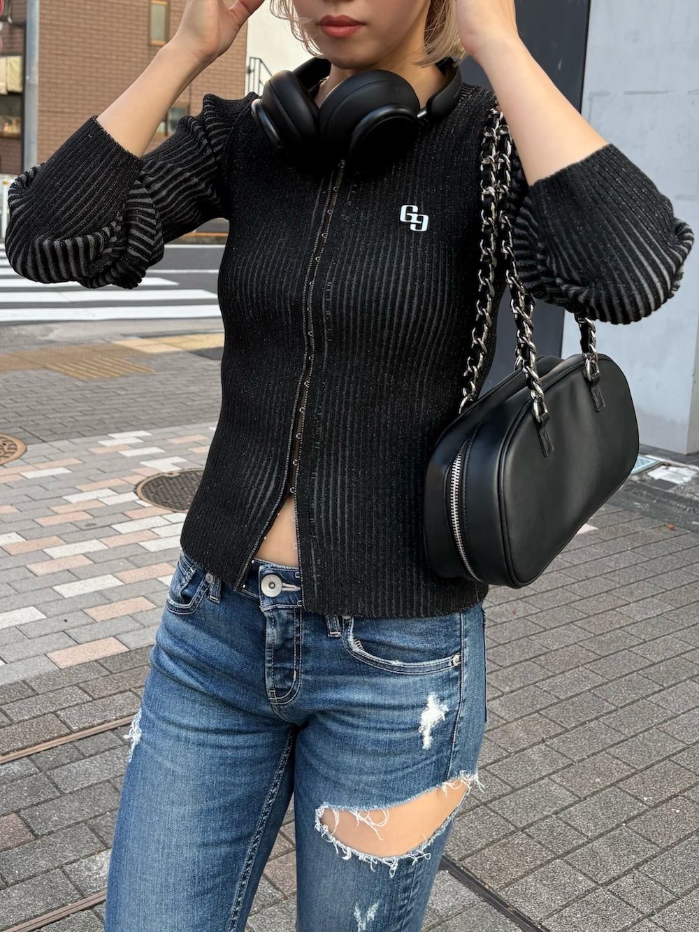 ブラック系のニット/セーター、ブルー系のデニムパンツ、ブラック系のブーツを着用したレディースの秋コーディネートの4枚目の写真