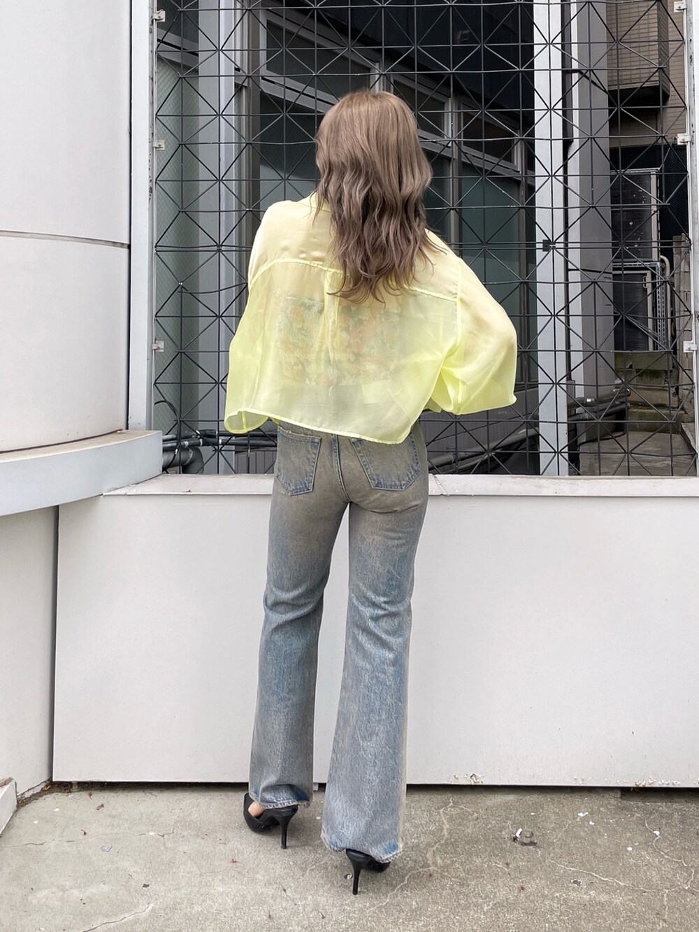 イエロー系のシャツ/ブラウス、ブラック系のチューブトップ、ブルー系のデニムパンツを着用したレディースの春コーディネートの3枚目の写真
