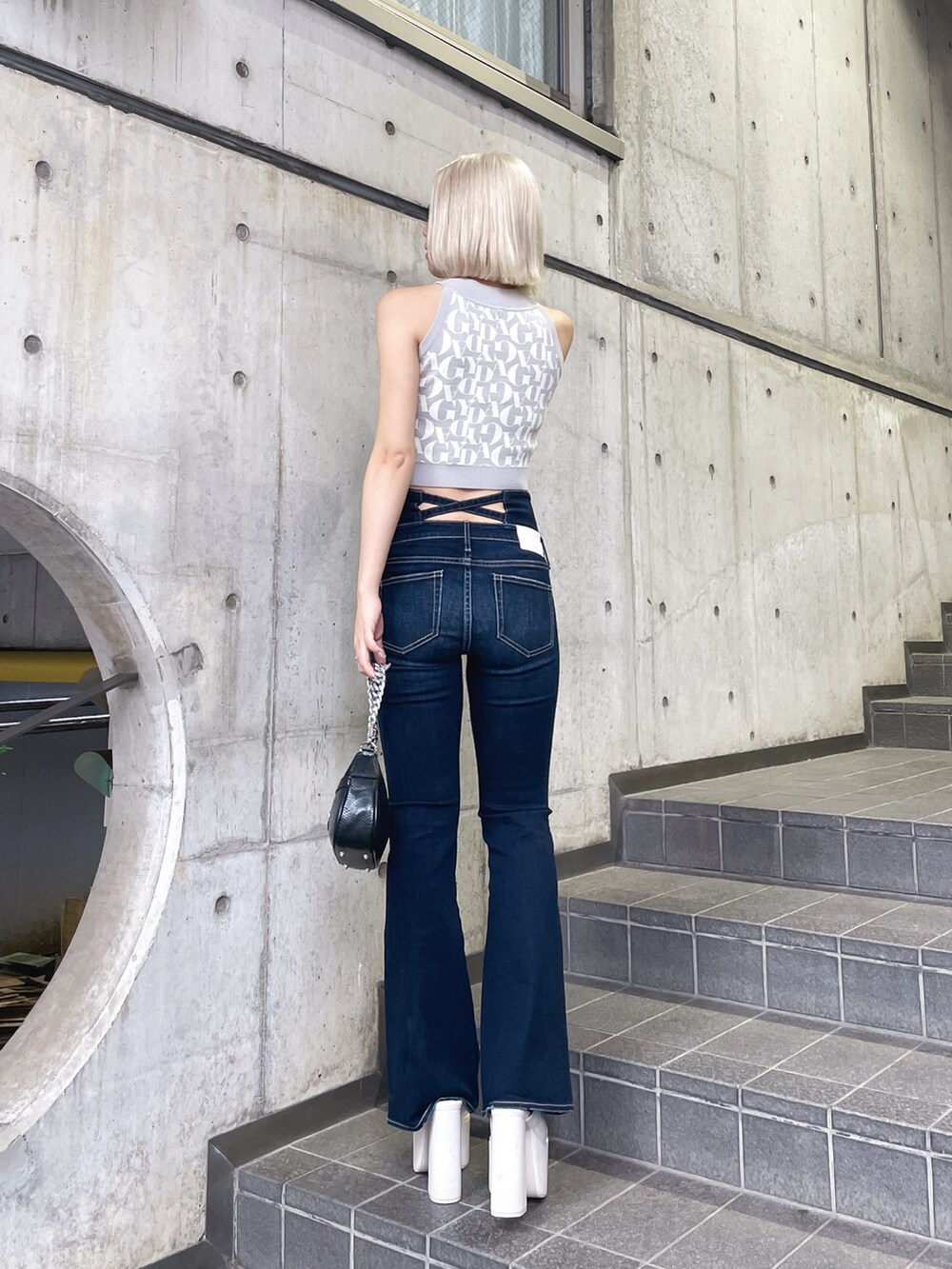 グレー系のニット/セーター、ブルー系のデニムパンツ、ブラック系のハンドバッグを着用したレディースの夏コーディネートの3枚目の写真