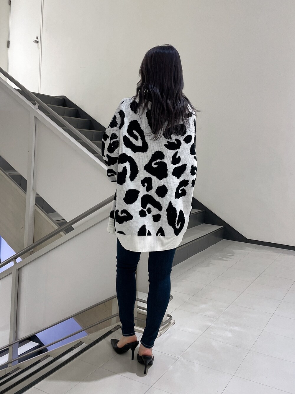 ブルー系のデニムパンツ、ブラック系のパンプス、ホワイト系のカーディガン/ボレロを着用したレディースの春コーディネートの3枚目の写真