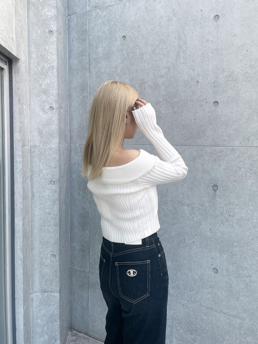 ホワイト系のニット/セーター、ブルー系のデニムパンツ、ホワイト系のパンプスを着用したレディースの冬コーディネートの4枚目の写真