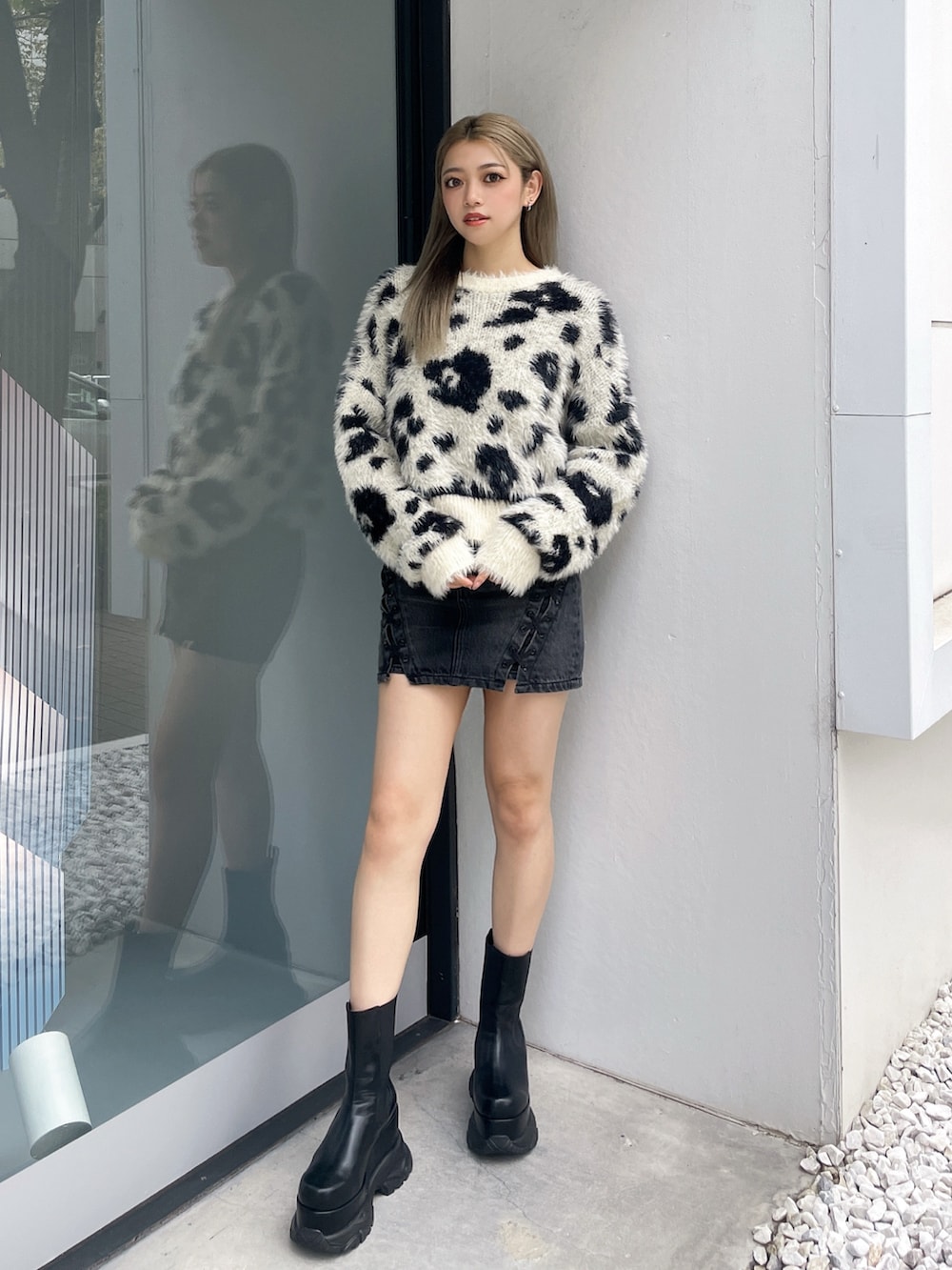 ホワイト系のニット/セーター、ブラック系のデニムスカート、ブラック系のブーツを着用したレディースの冬コーディネートの2枚目の写真