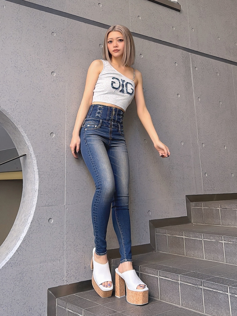 グレー系のタンクトップ、ブルー系のデニムパンツ、ホワイト系のサンダルを着用したレディースの夏コーディネートの2枚目の写真