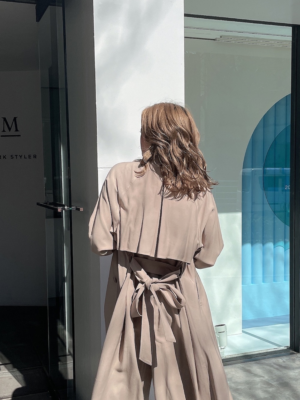 ホワイト系のニット/セーター、ベージュ系のトレンチコート、ブルー系のデニムパンツを着用したレディースの春コーディネートの5枚目の写真