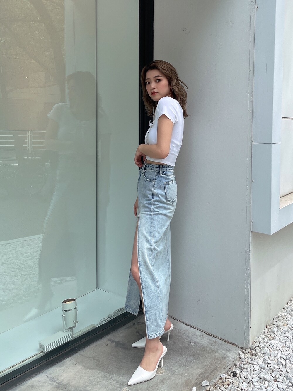 ブルー系のデニムスカート、ホワイト系のTシャツ/カットソー、ホワイト系のパンプスを着用したレディースの春コーディネートの2枚目の写真